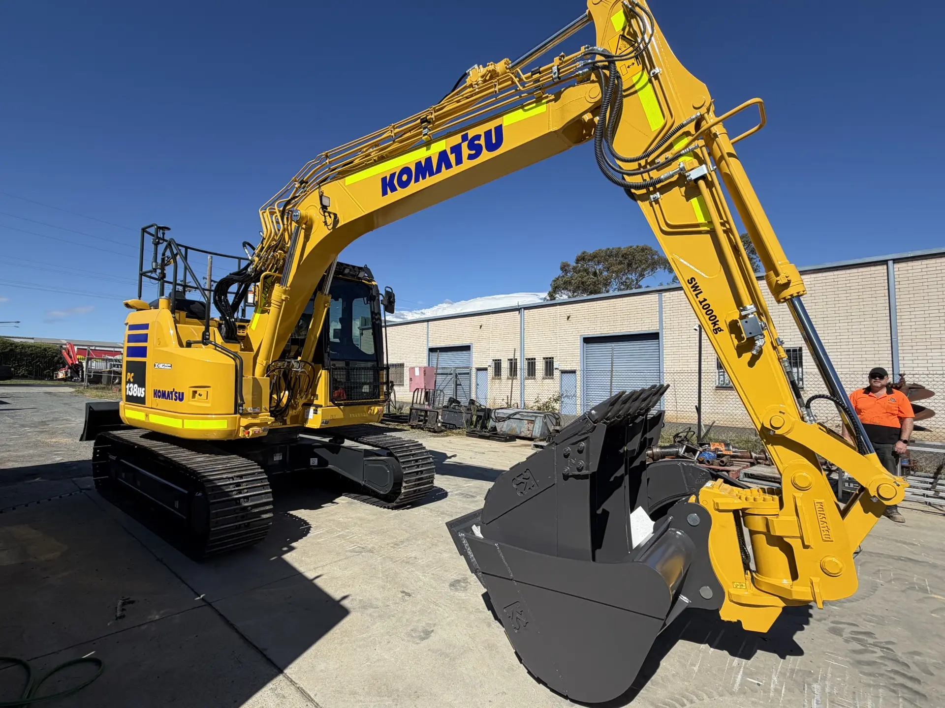 Yellow excavator with its arm raised in the hire yard