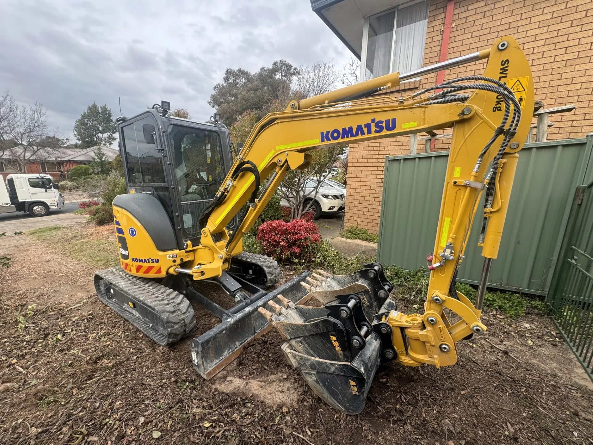 Yellow excavator digging beside a house on a Canberra residential block