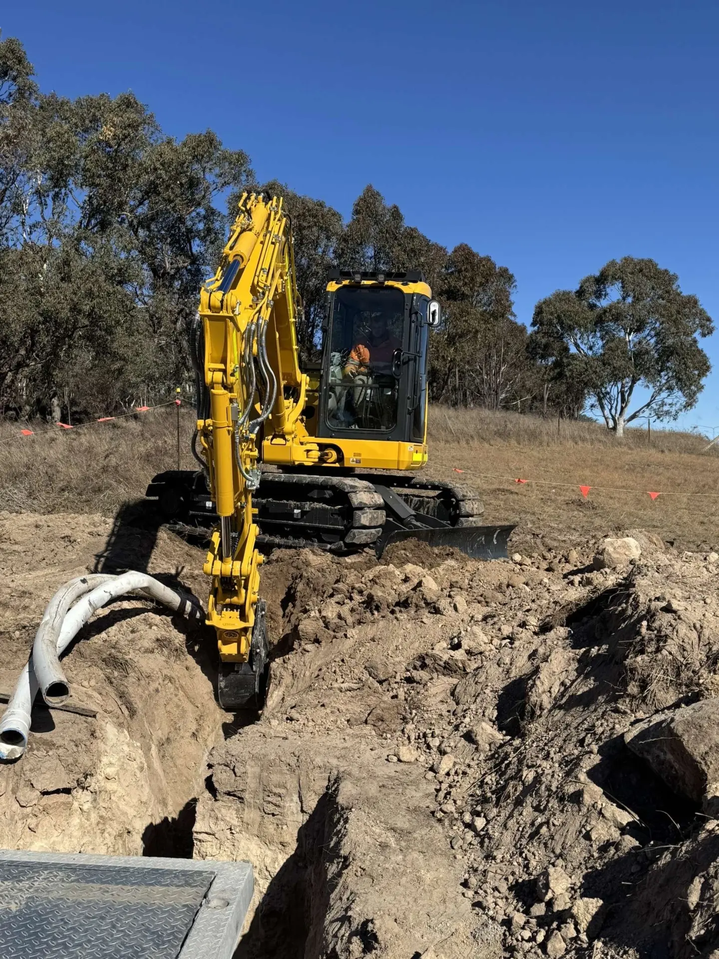 Excavator digging a trench on a rural hillside