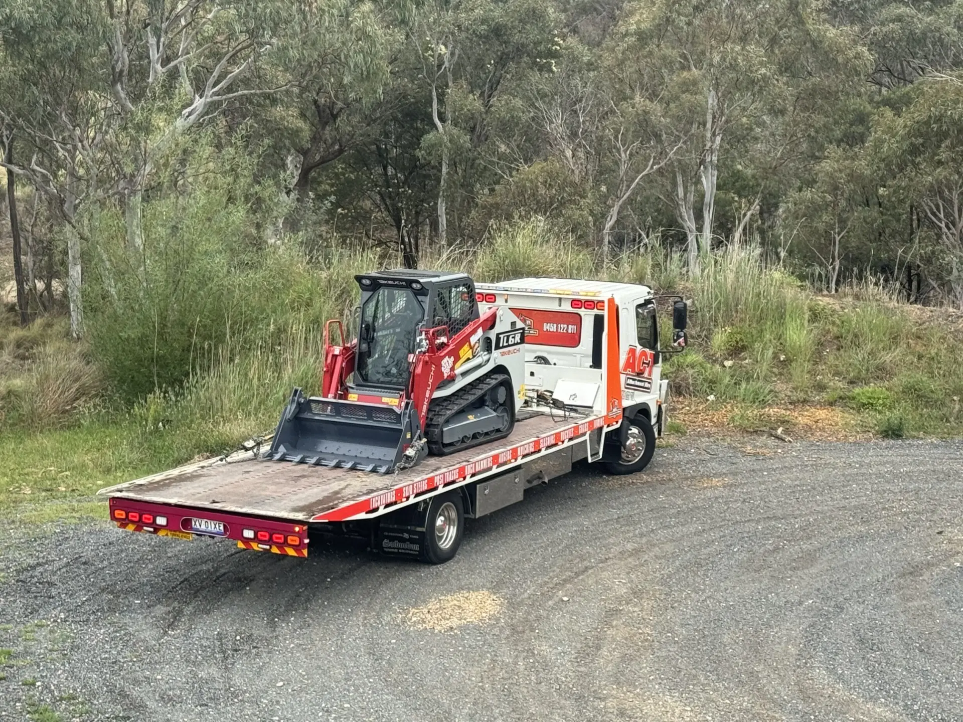 Skid steer loaded on the tow truck, on a bushland road
