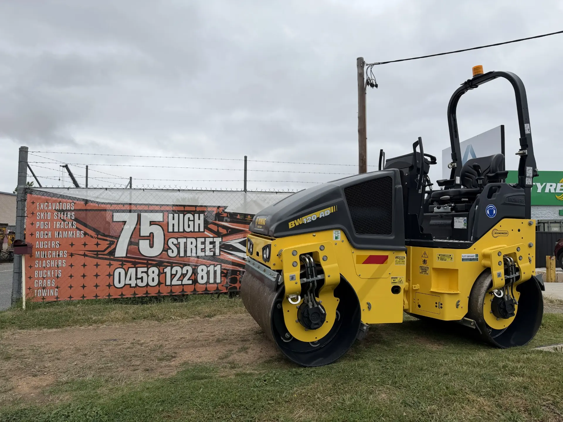 Yellow roller in the Queanbeyan East yard beside the 75 High St sign