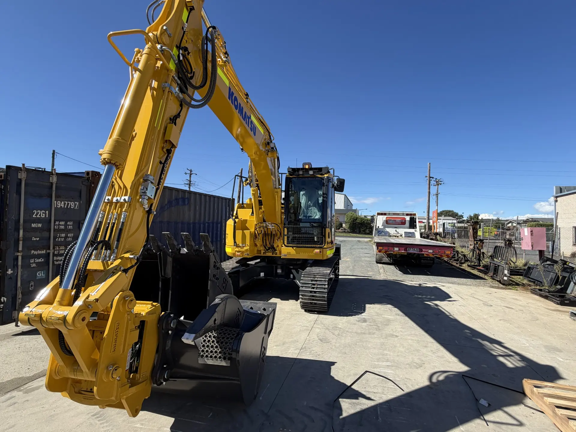 Excavator in the yard, shipping containers behind
