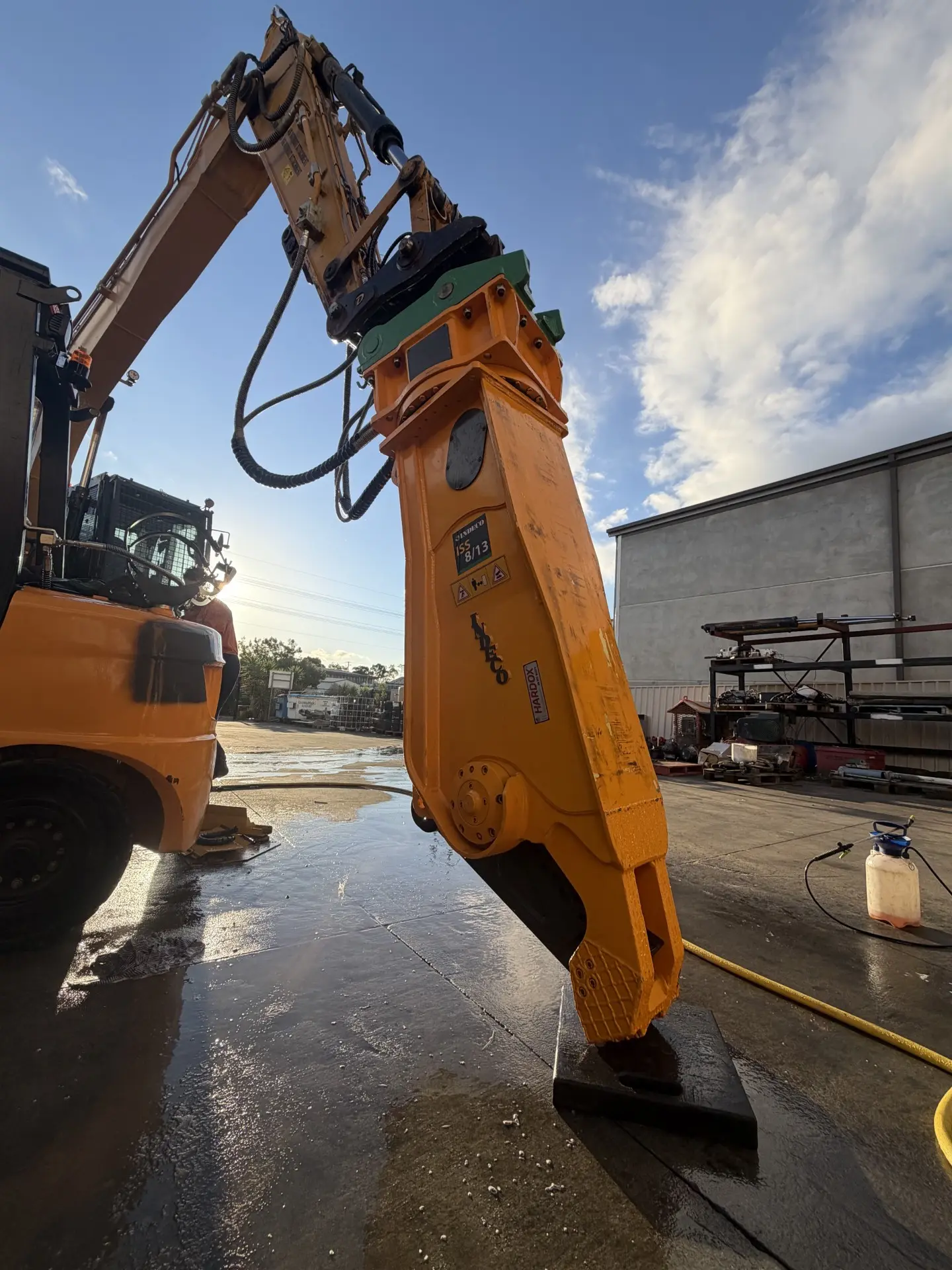 Hydraulic hammer attachment fitted to an excavator against a clear sky