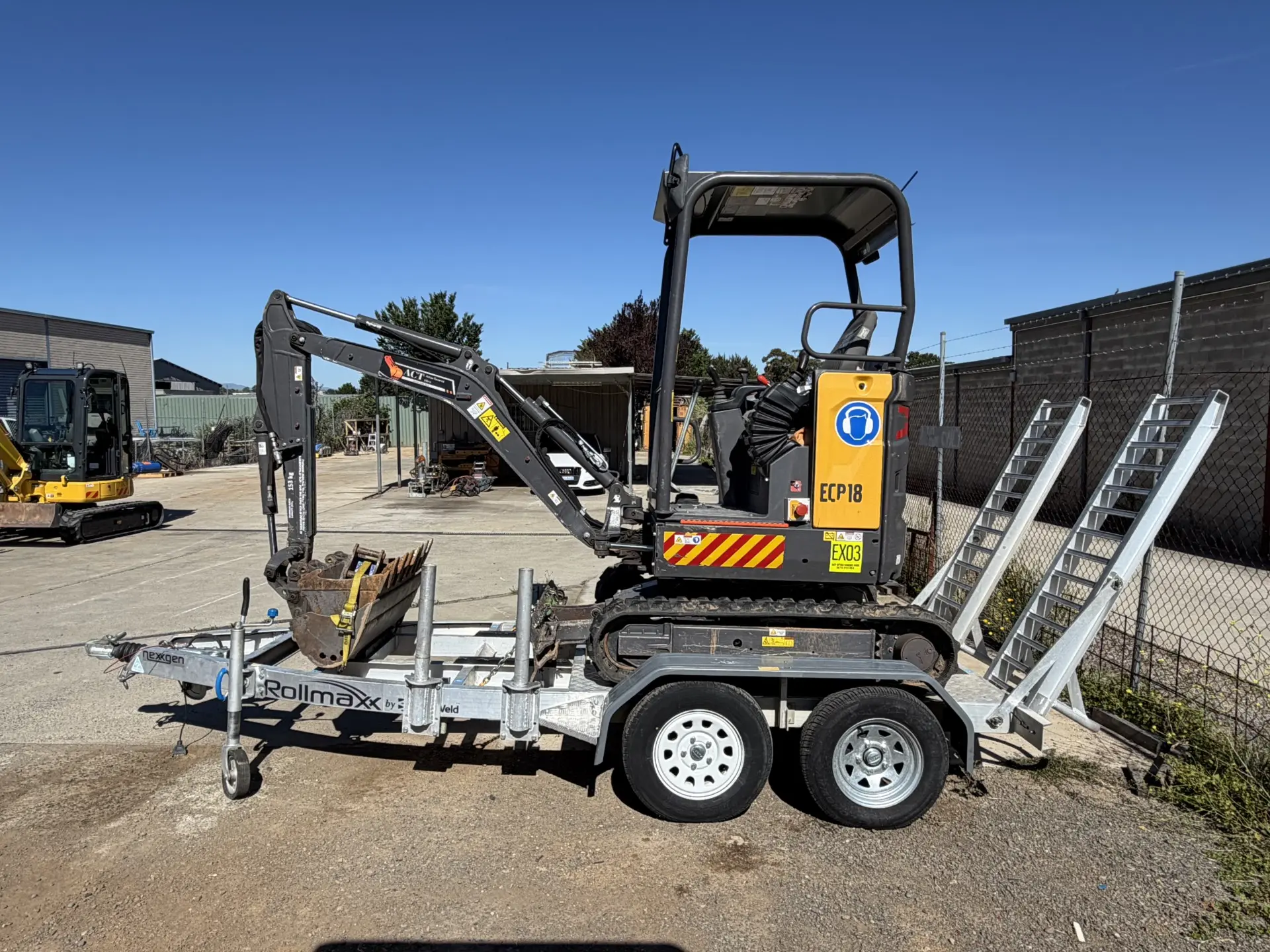 Mini excavator being loaded onto a trailer at the hire yard