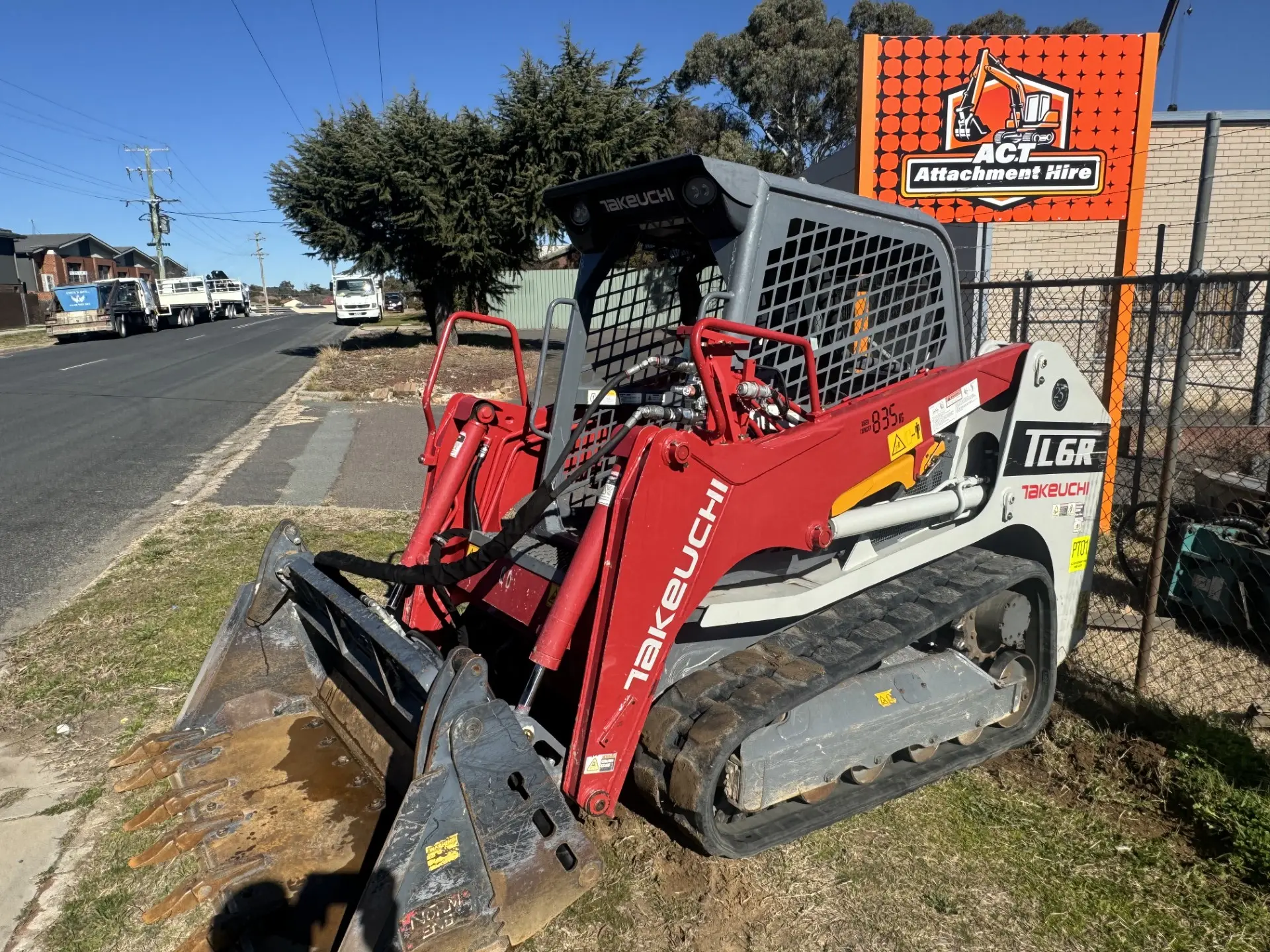 Red skid steer fitted with a grapple attachment on a street