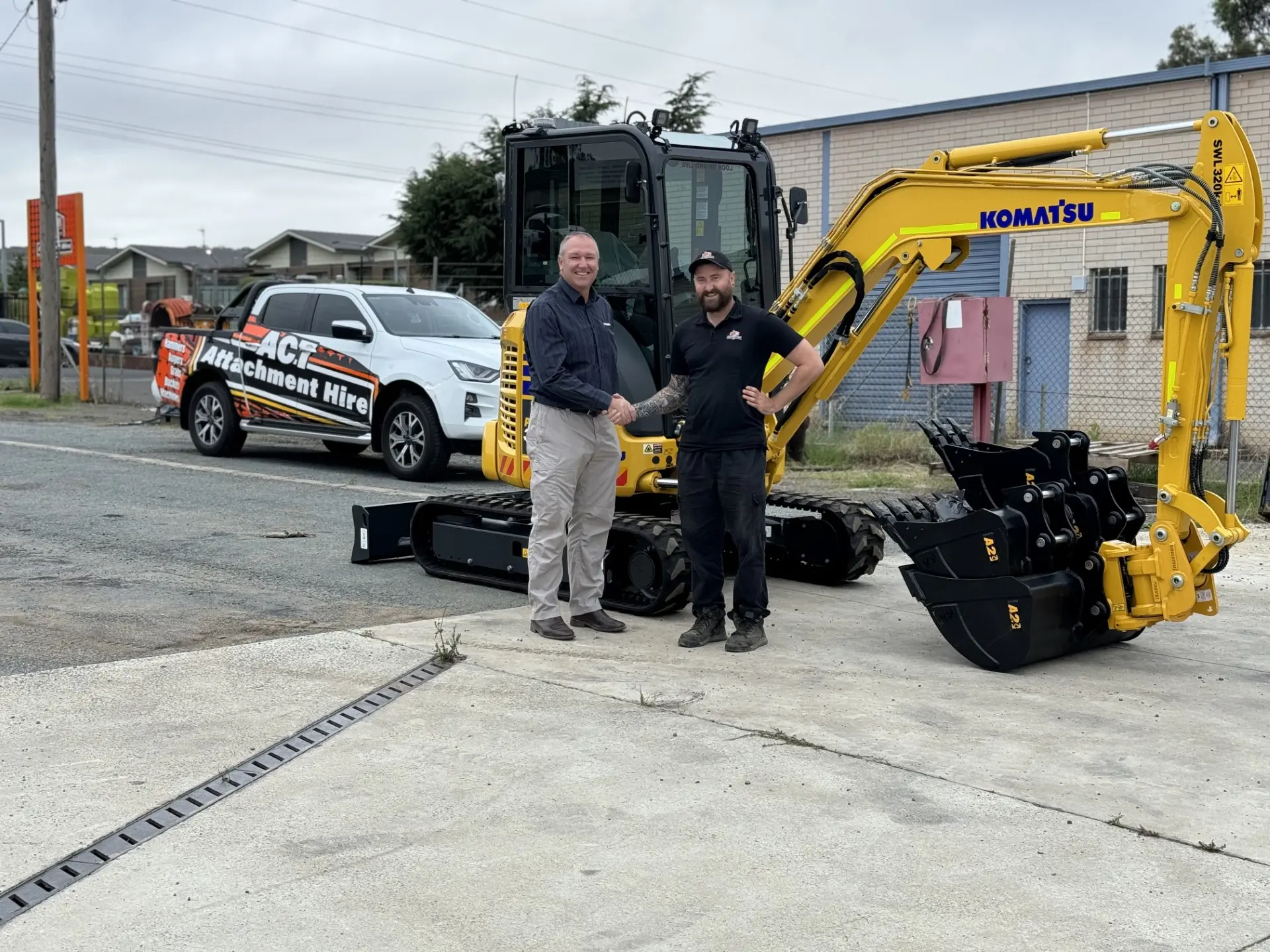 Two ACT Attachment Hire team members with an excavator on a trailer