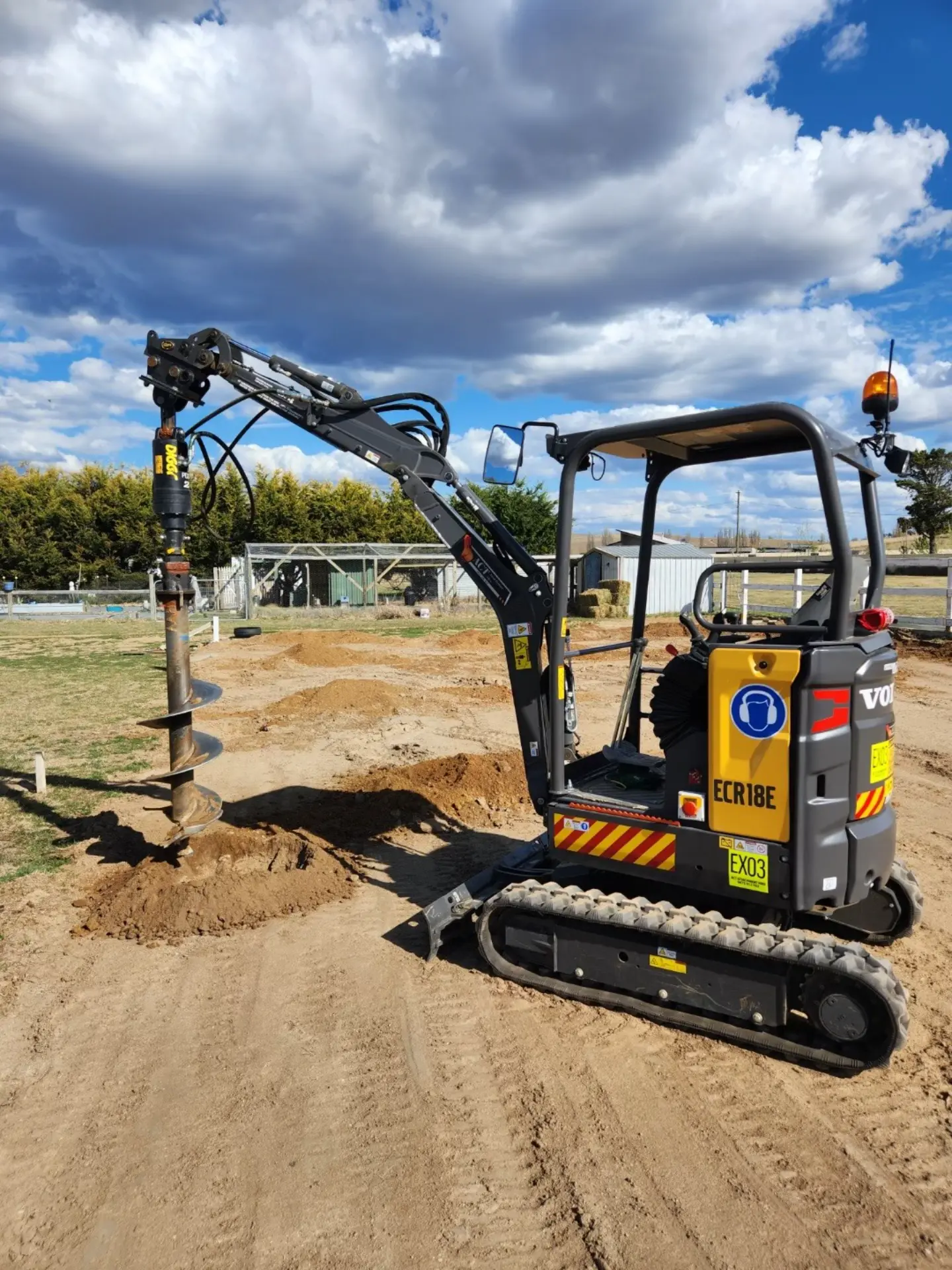 Mini excavator auger drilling a small hole in a yard